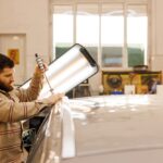 Mechanik opravuje preliačiny na aute po krupobití pomocou PDR techniky v autoservise.